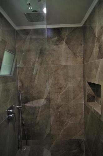 a bathroom with a shower with a glass door at Antigonis Garden House in Chania