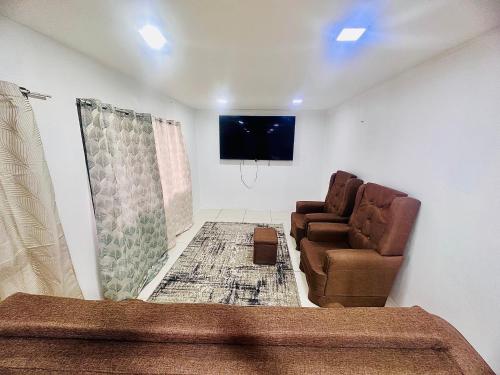 a living room with two chairs and a flat screen tv at HomeStay Inn in Suva