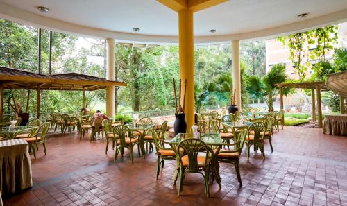 a restaurant with tables and chairs in a patio at Golf Course Hotel in Kampala