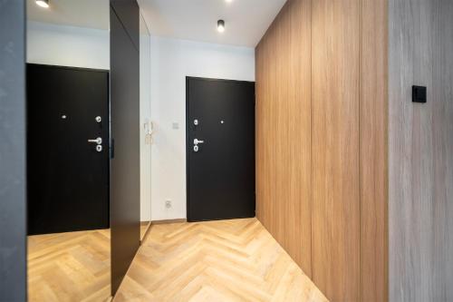 a hallway with three black doors and wooden floors at Apartament Piotrkowska 44 - studio in Łódź