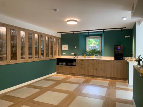 a large kitchen with green walls and wooden cabinets at HOTEL BOUTIQUE VILLA DEL MARQUÉS in Muros de Nalón