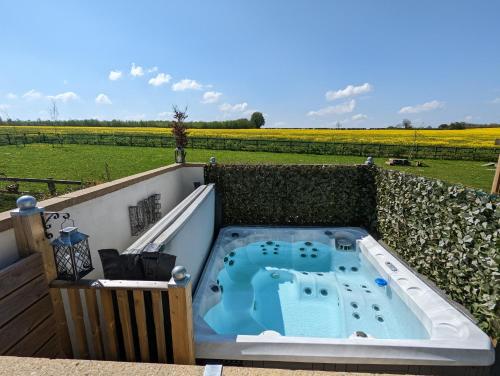 a hot tub on a balcony with a view of a field at Romantic Barn, Private Hot-Tub near Diddly Squat 2 or 3 night stays in Chipping Norton