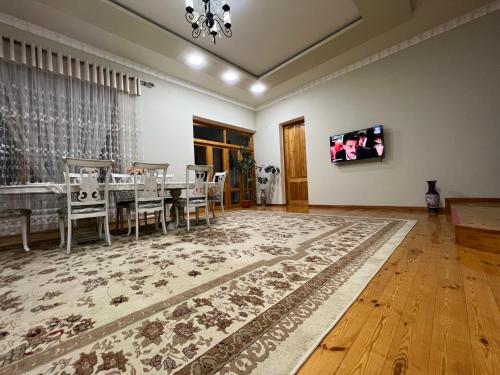 uma sala de jantar com mesa e cadeiras e uma televisão em Brown Hill em Samarkand
