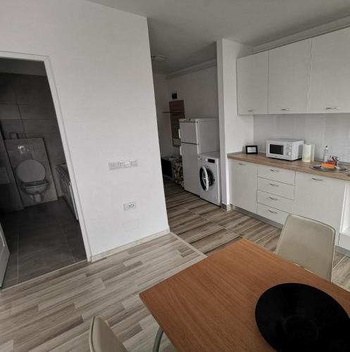 kuchnia z białymi szafkami oraz stołem i krzesłami w obiekcie New Apartament Baia Mare 20 w mieście Baia Mare