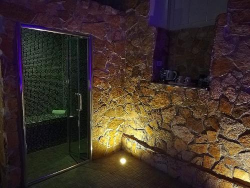 La salle de bains est pourvue d'une douche à l'italienne à côté d'un mur en pierre. dans l'établissement SPA SUITE SICILIA, à Rosolini