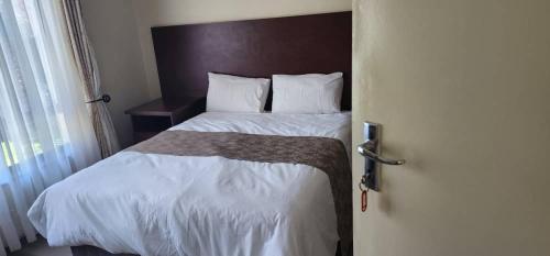 a bedroom with a bed with a wooden head board at Mandara Beeston guest house in Harare