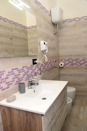a bathroom with a sink and a toilet and a mirror at B&B Royal Palace of Napoli & Reggia di Caserta in Caserta