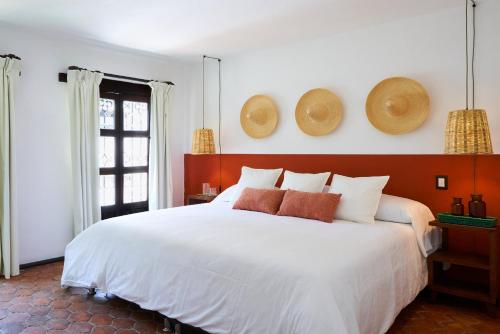 a bedroom with a large white bed with hats on the wall at AmazINN Stay CDMX Coyoacan in Mexico City