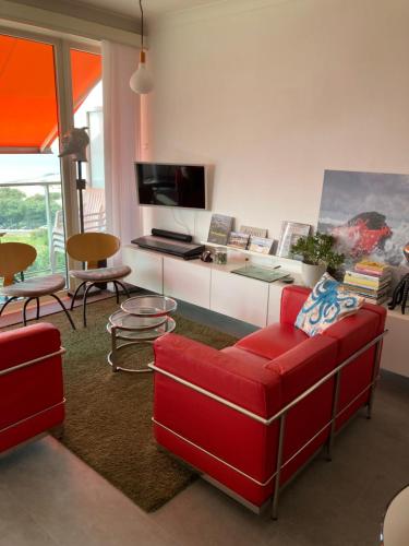 uma sala de estar com um sofá vermelho e uma mesa em SEA THE SEA - FEEL THE SEA - TOUCH THE SEA em Bredene