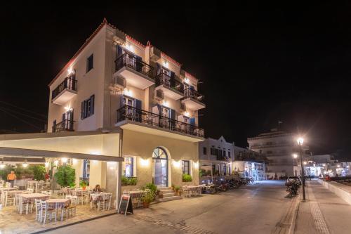 un gran edificio blanco con mesas y sillas por la noche en Stelios Hotel, en Spetses