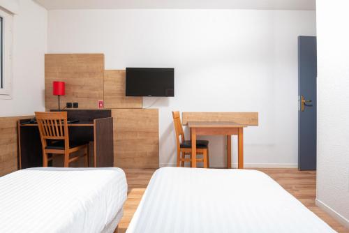 a hotel room with two beds and a desk and a television at Apparthotel Privilodges Lyon Lumière in Lyon