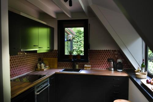 kuchnia z zielonymi szafkami, umywalką i oknem w obiekcie Boshuisje Rekem - Topo w mieście Lanaken