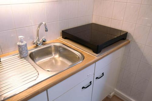 uma cozinha com um lavatório e um balcão com uma garrafa em 'T Heilige Pad em Egmond aan Zee