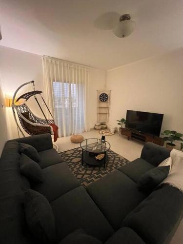 شقة الاحلام في King Abdullah Economic City: غرفة معيشة مع أريكة سوداء وتلفزيون