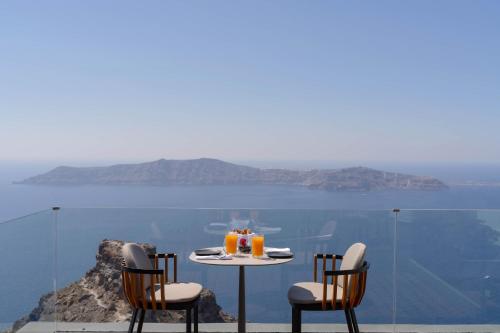 a table and chairs with a view of the ocean at Kivotos Santorini - Preferred Hotels & Resorts in Imerovigli