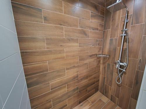a bathroom with a shower with a wooden wall at Apartment on Belvedere in Ivano-Frankivsʼk