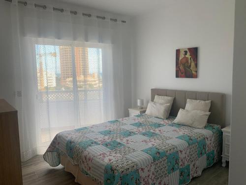 um quarto com uma cama com uma colcha e uma janela em VAUMAR APARTMENT - SEA VIEW em Portimão