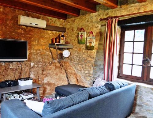 un soggiorno con divano blu e parete in pietra di La Pinay - Une petite maison cosy avec spa & cheminée a Lacave