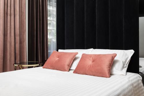 białe łóżko z 2 pomarańczowymi poduszkami w obiekcie City of the Kings - Onyks Apartment w Krakowie