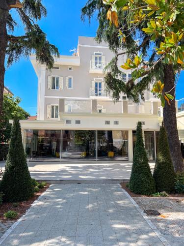 a large white building with trees in front of it at Doride Suites Boutique Hotel in Marina di Carrara
