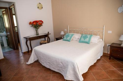 a bedroom with a bed and a table with a vase of flowers at Agriturismo Sa Mendhula in Cugnana