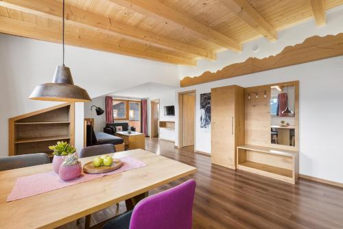 ein Esszimmer und ein Wohnzimmer mit einem Holztisch und lila Stühlen in der Unterkunft Berghaus Mucha - Ferienwohnungen - Naturpark Partner in Bolsterlang