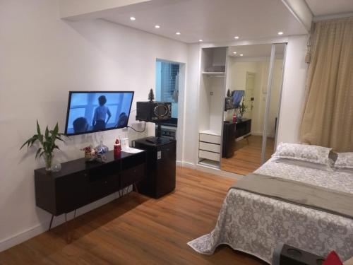 1 dormitorio con 1 cama y TV de pantalla plana en Vem pro Arouche/República -Studio- 4 min do Metrô, en São Paulo