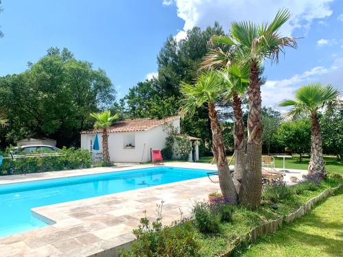 una piscina con palmeras y una casa en Aix-Marseille superbe T2 avec jardin, piscine et parking, en Simiane-Collongue