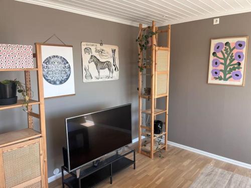 a living room with a flat screen tv and shelves at Vakker lelighet nær sentrum. in Kristiansand