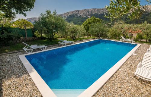 a swimming pool with two lawn chairs next to it at Apartmani M in Baška
