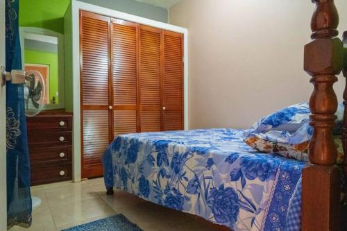 een slaapkamer met een bed met een blauwe en witte sprei bij Perfect Family Home Close to Roseau in Roseau