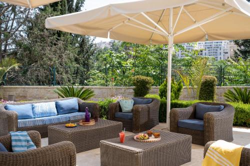 a patio with chairs and tables and an umbrella at Hotel Yehuda in Jerusalem