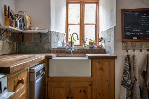 a kitchen with a sink and a window at Woodview - cosy 1840s cottage in Chew Valley and Mendip AONB in Compton Martin