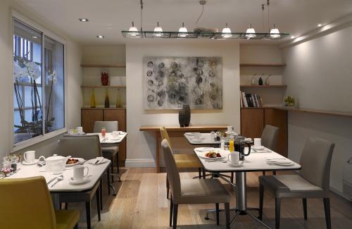 a restaurant with white tables and chairs and a dining room at Sydney House Chelsea in London