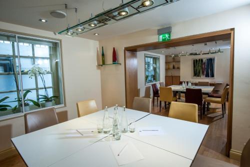 a dining room with a white table and chairs at Sydney House Chelsea in London