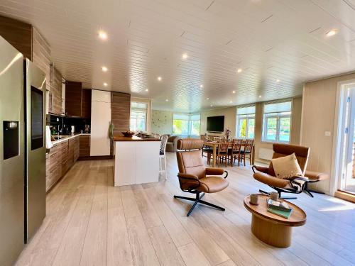cocina y sala de estar con sillas y mesa en Hardangerfjord View - luxury fjord-side holiday home, en Øystese