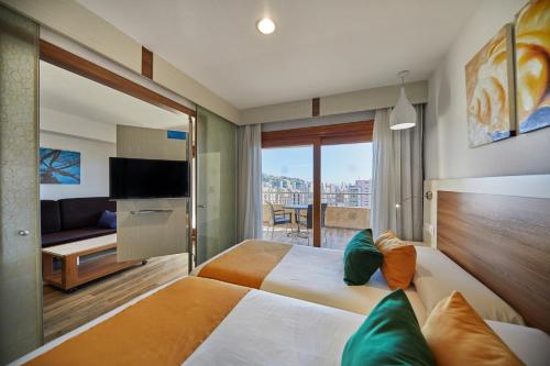 a hotel room with two beds and a television at Sandos Benidorm Suites in Benidorm