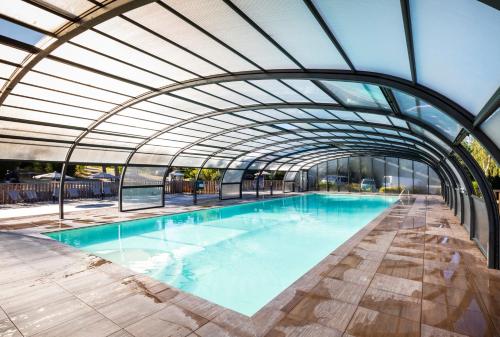 una piscina cubierta con techo de cristal en Huttopia Lac de la Siauve, en Lanobre