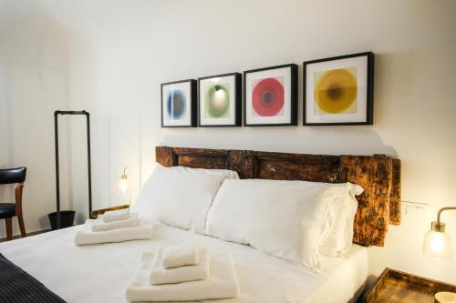 a bedroom with a white bed with three pictures on the wall at Casa Alta in LʼAquila
