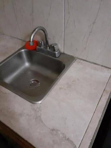 a sink in a kitchen with a red sponge on it at Cosy Corner in Saint Georgeʼs