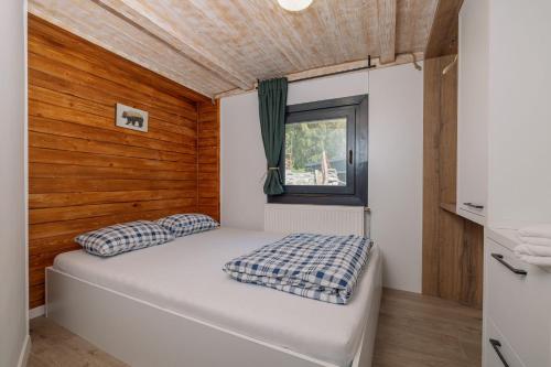 a small bedroom with a bed and a window at Cabana Bucin in Bucsin