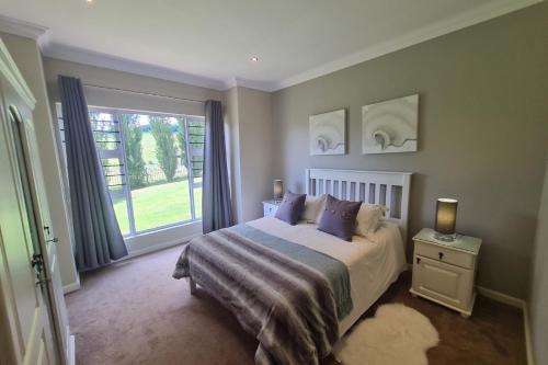 a bedroom with a bed and a large window at 25 Hazyview Drakensburg Mountain Views in Underberg