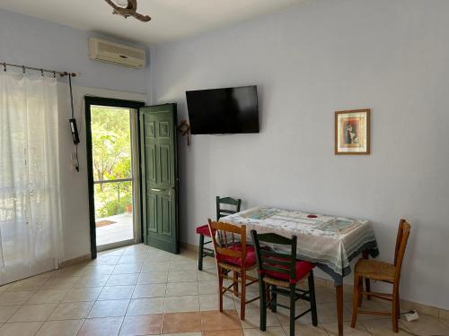 a dining room with a table and chairs and a television at Orange Tree Garden in Pefkochori