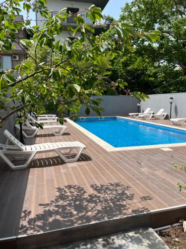 una terraza de madera con sillas y una piscina en Cozy Rooms, en Kobuleti