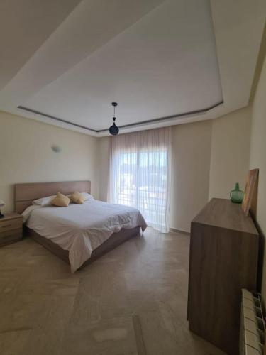 um quarto com uma cama e uma grande janela em Immense appartement familial haut de l agdal em Rabat