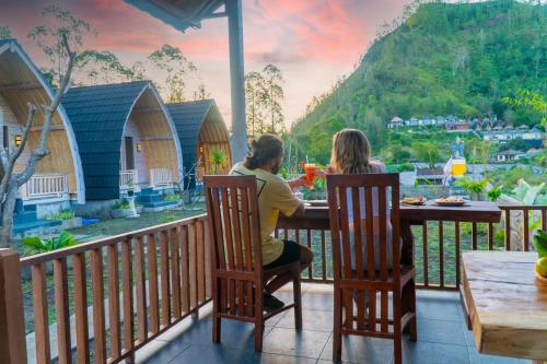 two women sitting at a table on a balcony with a view at Batur cottage in Kubupenlokan
