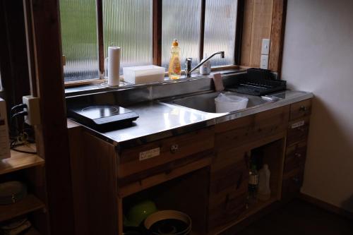 a kitchen counter with a sink and a window at 古民家ゲストハウス結舎-YUINOYA- in Nakanoto