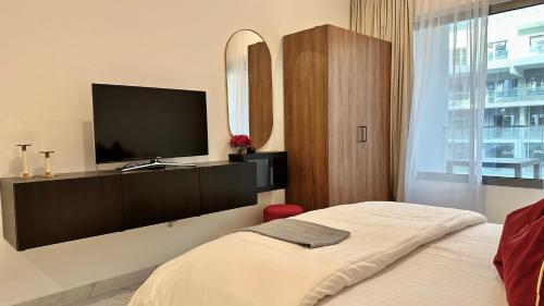 a bedroom with a flat screen tv and a bed at Cozy Studio In Masdar City in Al Qurayyah