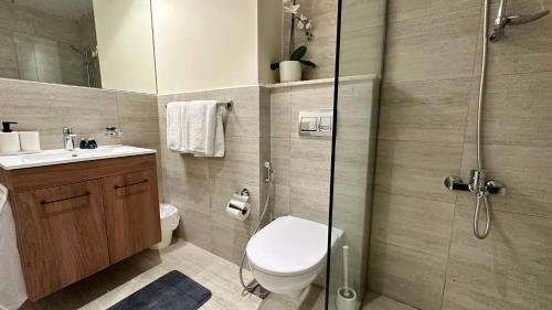 a bathroom with a toilet and a glass shower at Cozy Studio In Masdar City in Al Qurayyah