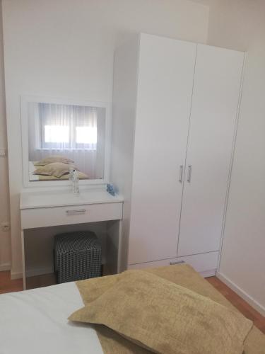 a white bedroom with a bed and a mirror at Laurus Makarska Accommodation in Makarska